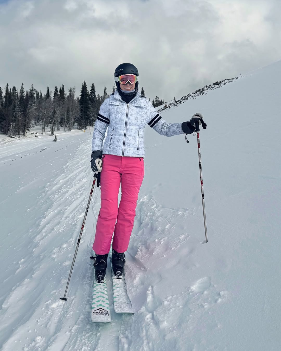 Skier wearing bright pink FERA waterproof snow pants on a snowy slope, designed for warmth, dryness, and flexible movement.